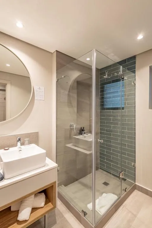 En-suite bathroom with a glass-walled shower, double basin vanity and round mirror
