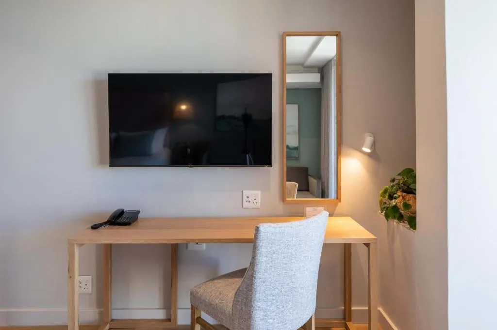 Room desk nook with a wall-mounted TV, telephone and a tall mirror beside a potted plant