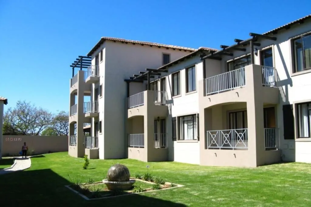 Three-storey apartment block with pergola-topped balconies set around a manicured lawn