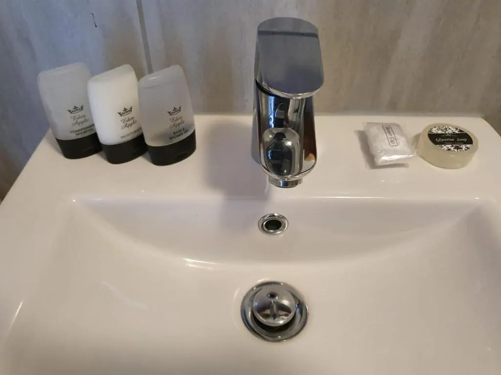 Close-up of the bathroom basin with branded toiletries, wrapped soap and a folded flannel