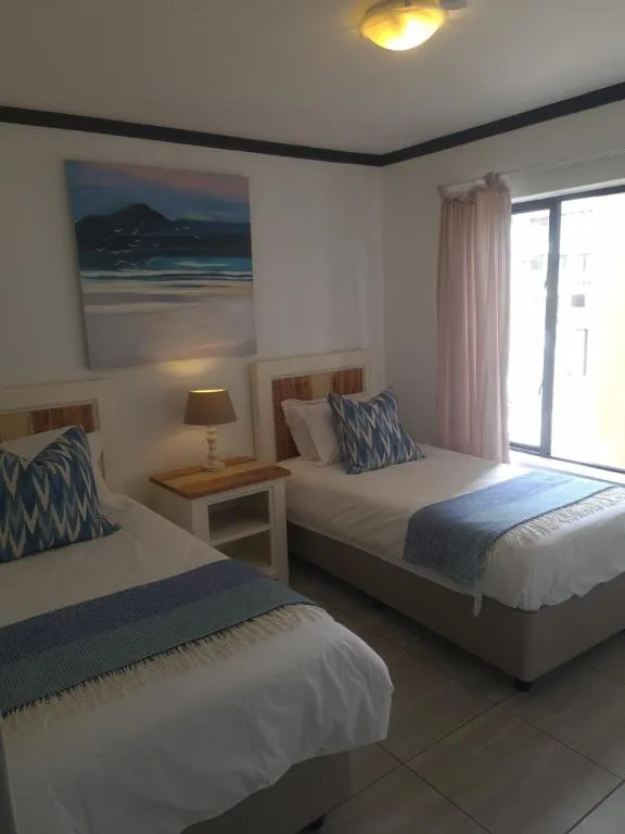 Twin bedroom with a framed mountain and beach painting hung above the two headboards