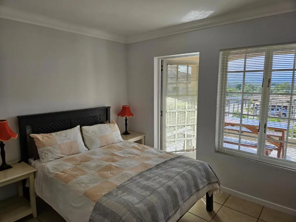 Bedroom with a private balcony and window looking over the estate towards distant mountains
