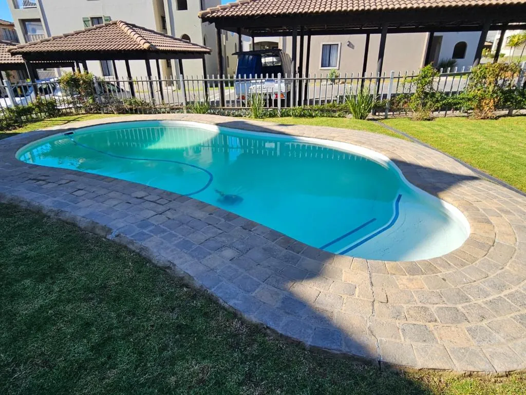 Communal kidney-shaped pool in a landscaped garden shared with the surrounding complex