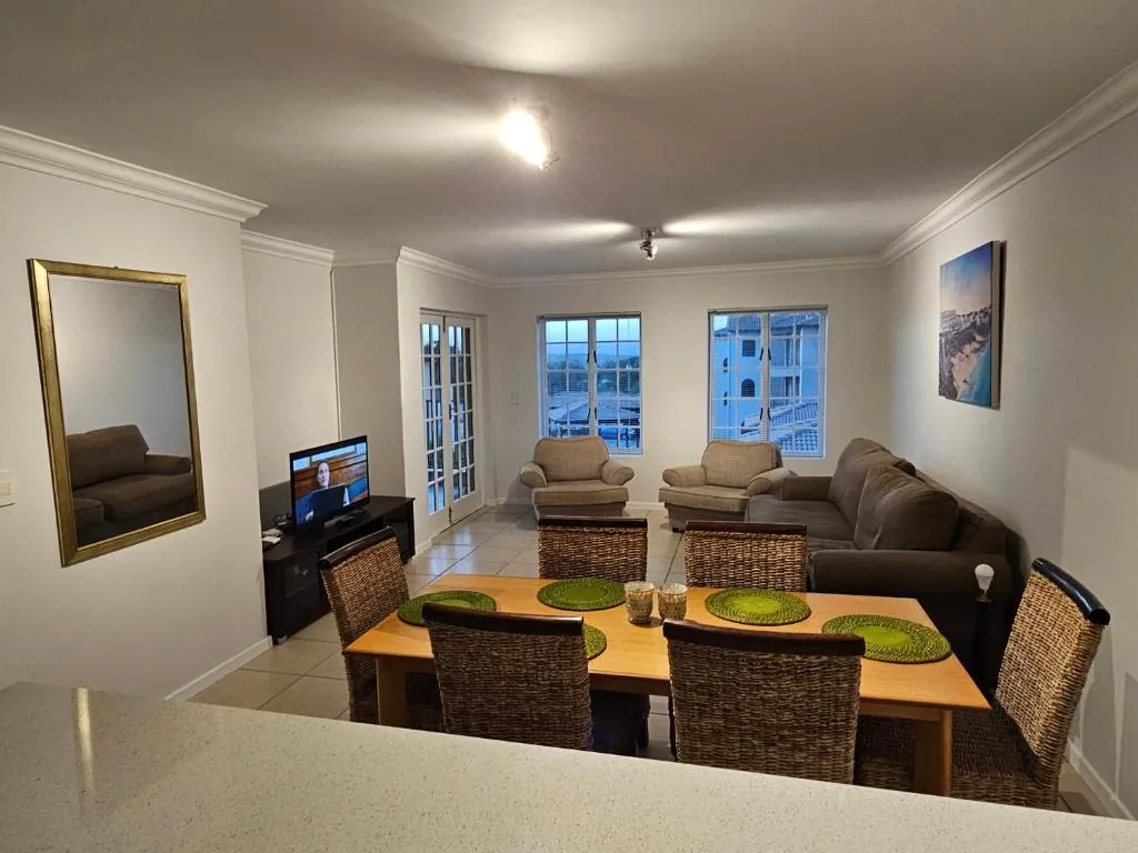 Living and dining area with a grey sofa, wooden dining table and coastal artwork