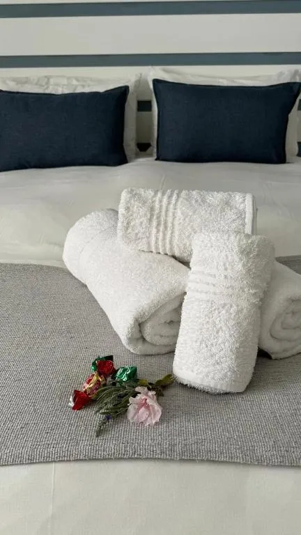 Rolled white towels and fresh flowers arranged on the foot of the bed