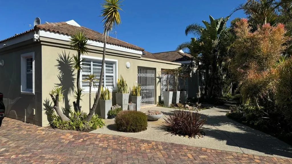 Guesthouse exterior with tiled roof, palm trees and a landscaped tropical garden path