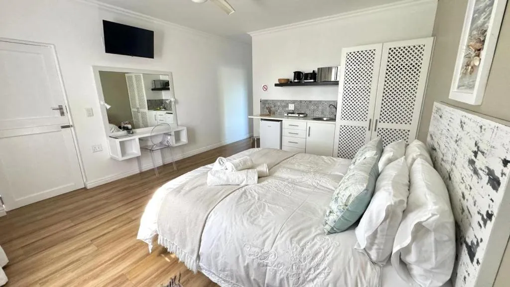Studio bedroom with kitchenette, wall-mounted TV and dressing table mirror