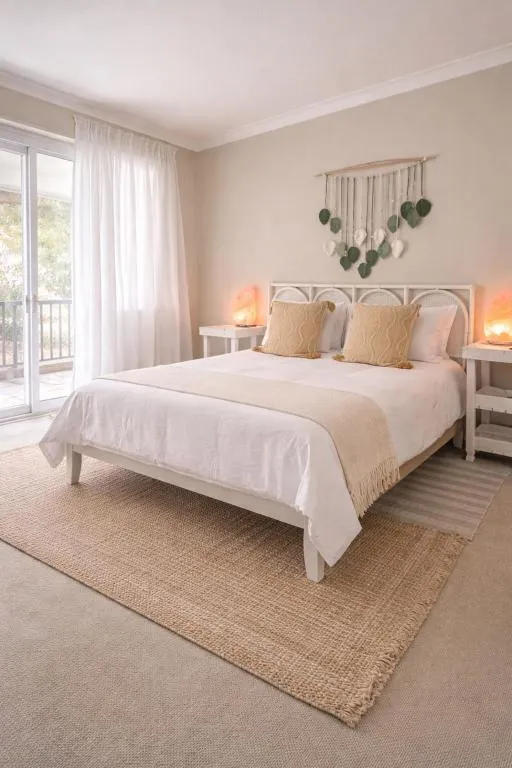 Bedroom with a rattan cane headboard, pompom wall hanging and a salt lamp
