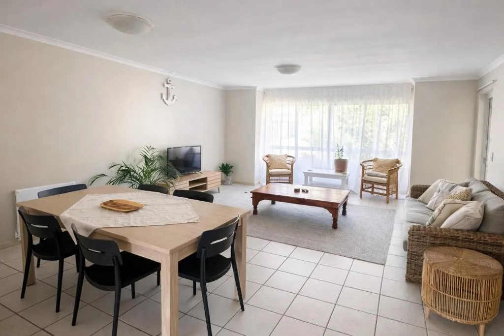 Open living and dining room with a six-seat table and wicker armchairs by the window