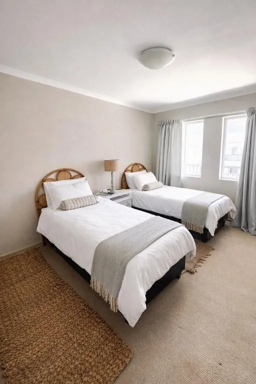 Twin bedroom with matching rattan headboards and grey throws
