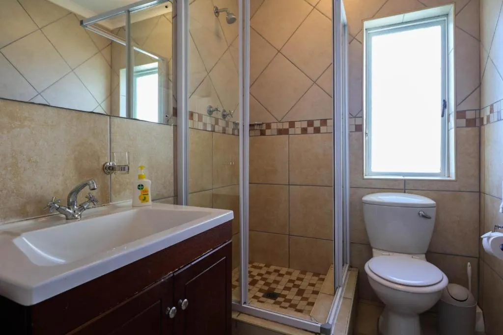 Bathroom with diamond-pattern tiling, a glass shower enclosure and a window