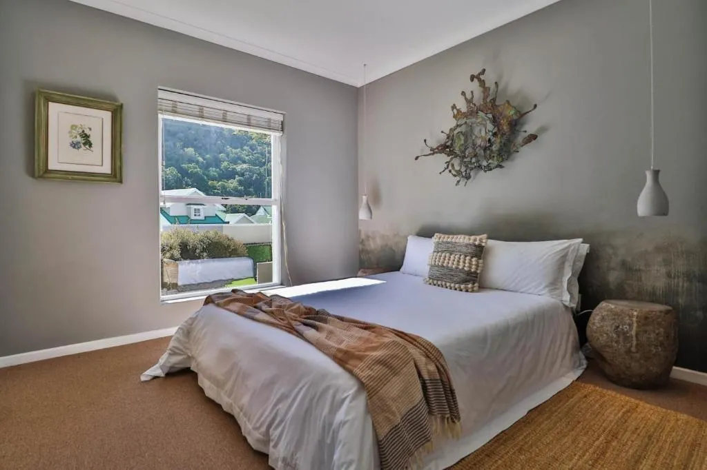 Bedroom with a grey feature wall, textile wall hanging and a window over the hillside