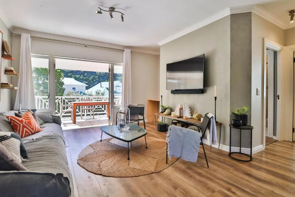 Lounge with a wall-mounted TV and glass coffee table opening onto the balcony