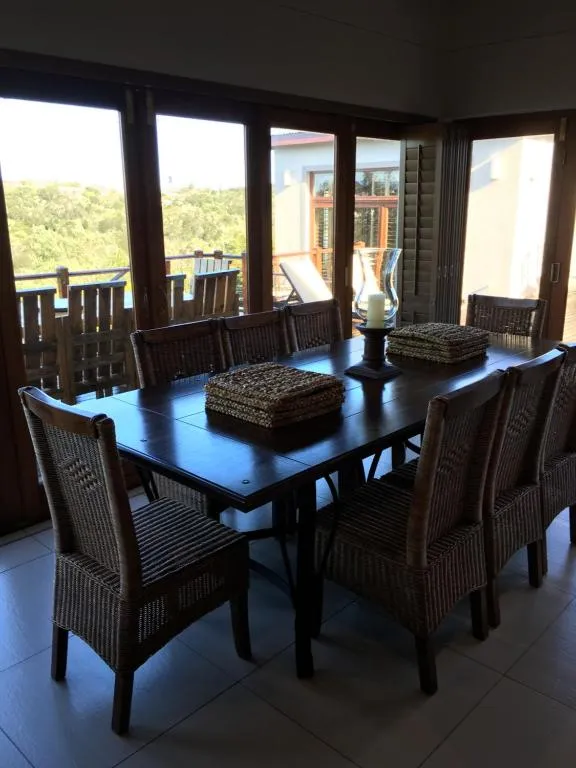 Dining room with woven wicker chairs and folding doors onto a valley-view balcony