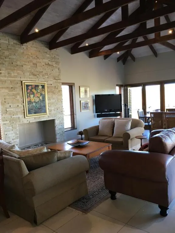 Living room with a vaulted timber-beam ceiling, stone fireplace and leather sofas