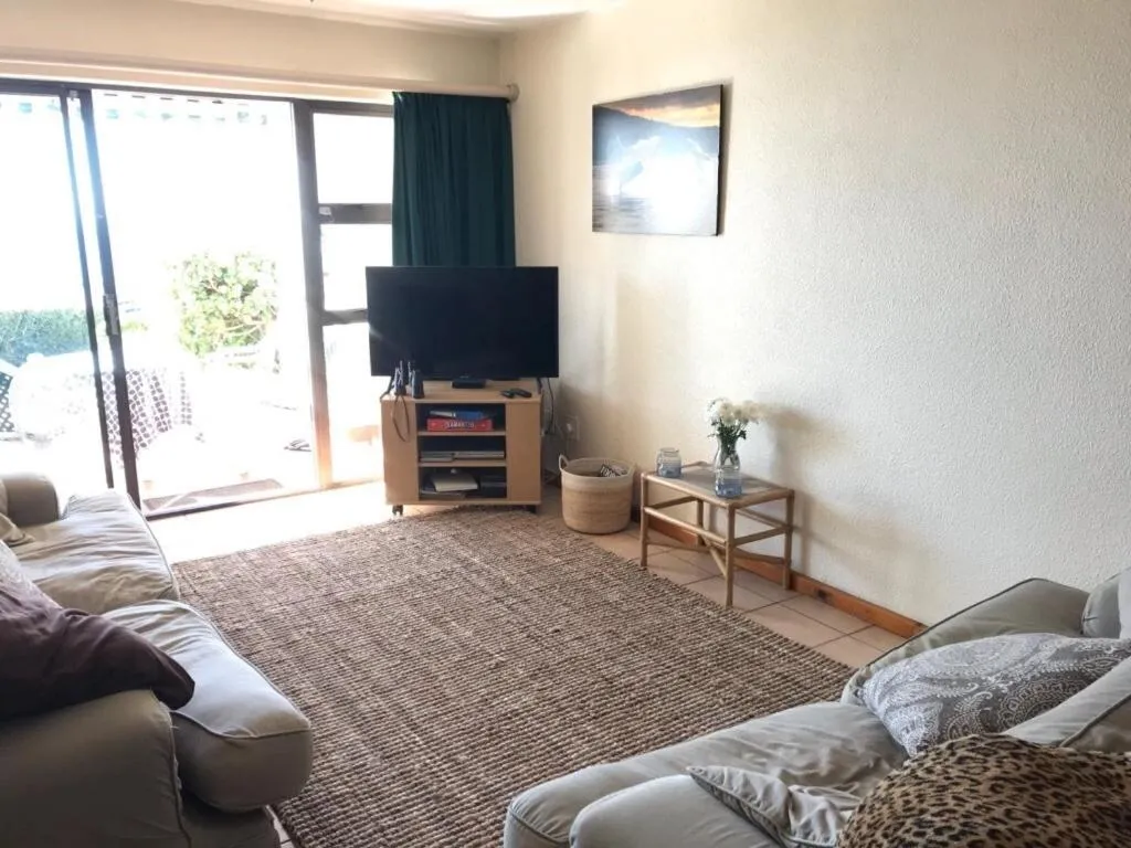 Second living space with sliding doors to the outside, TV console and seating in muted tones