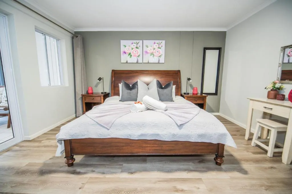 Bedroom with a dark wood sleigh bed, floral prints, and rolled towels laid on the linen