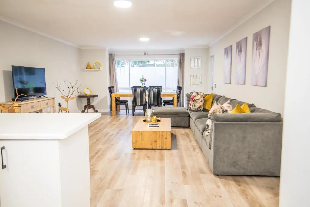 Living and dining area with a striped-chair dining table and sliding doors onto a walled patio