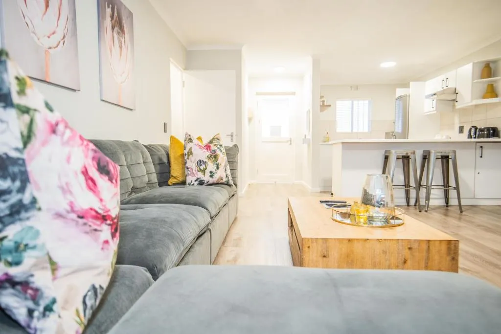 Living room sofa with floral scatter cushions looking through to the kitchen counter