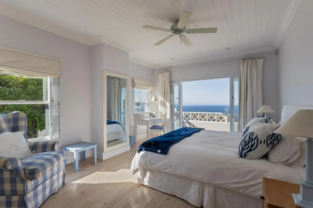Bedroom with a checked armchair and sliding doors opening onto a sea-view balcony