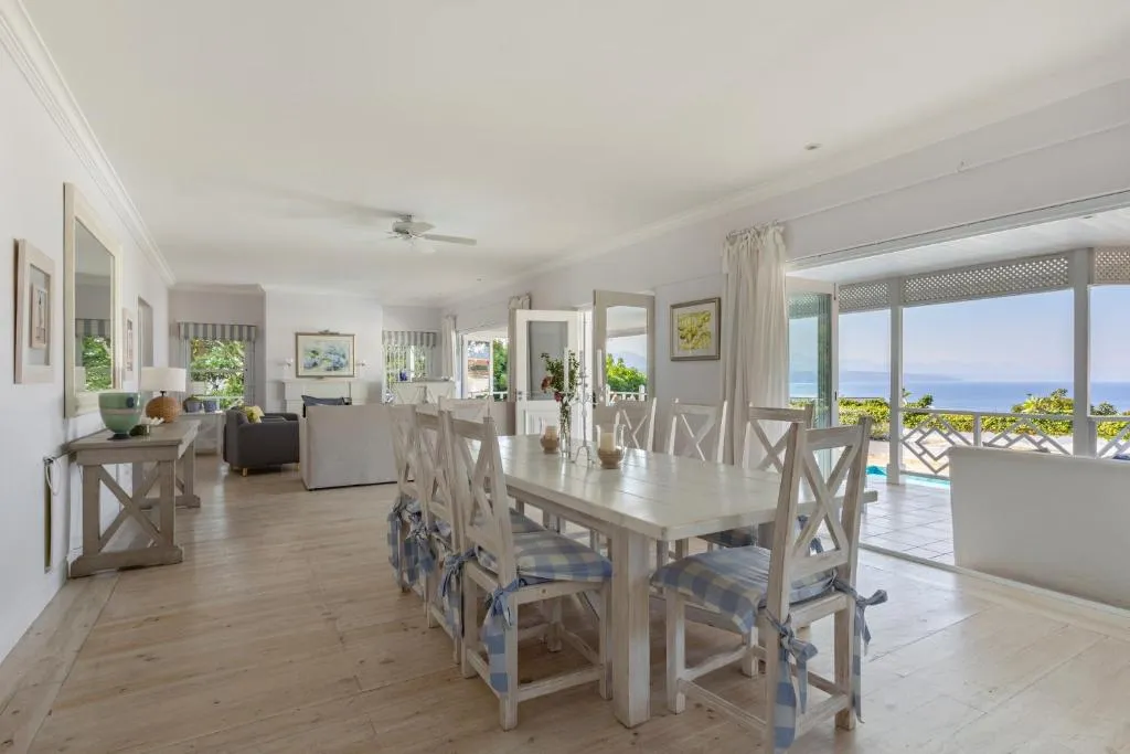 Long dining table for ten opening onto a screened porch with a sea view