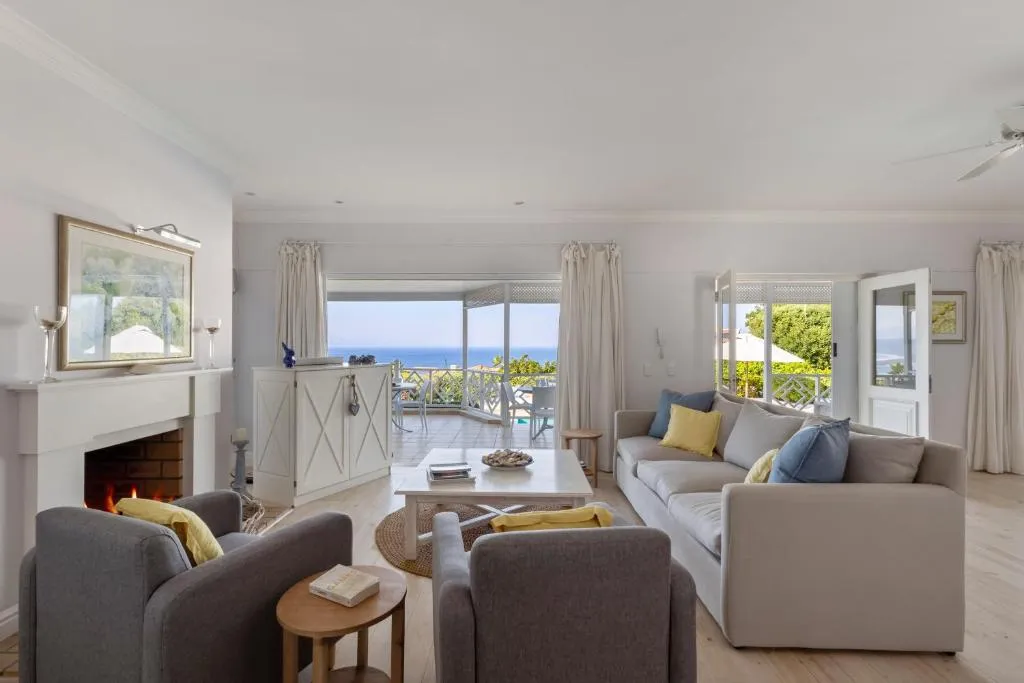 Living room with a lit brick fireplace, sofas and doors open to the pool and sea view
