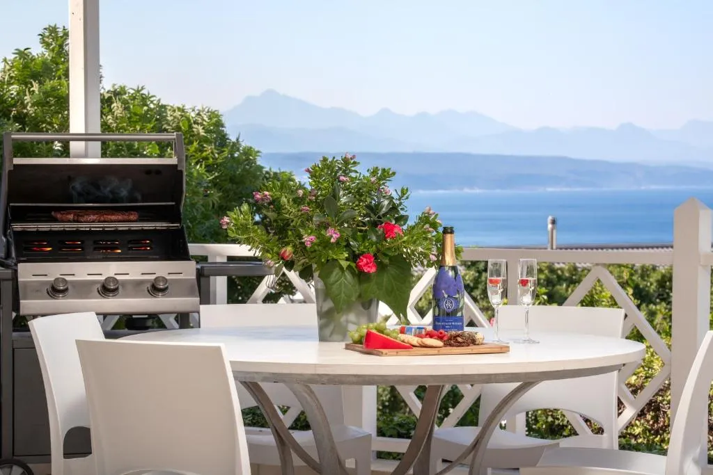 Outdoor patio with a gas braai and a set dining table overlooking the sea and mountains