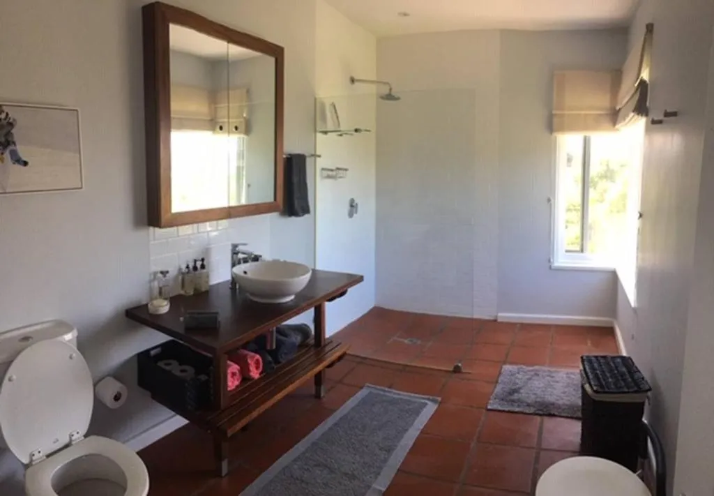 Bathroom with a freestanding vanity, walk-in shower and terracotta tile floor