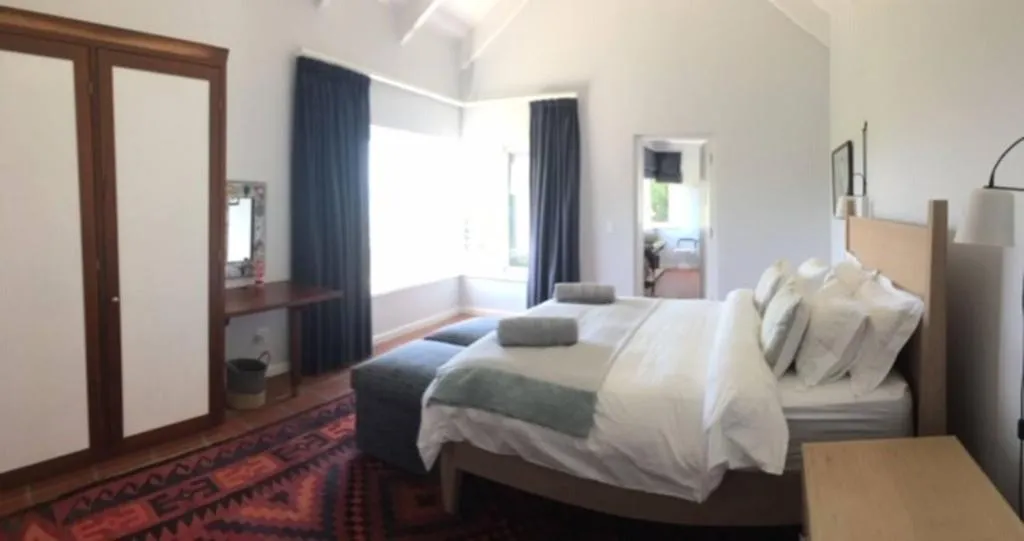 Bedroom with vaulted ceiling, dark wardrobe and patterned rug beside a double bed