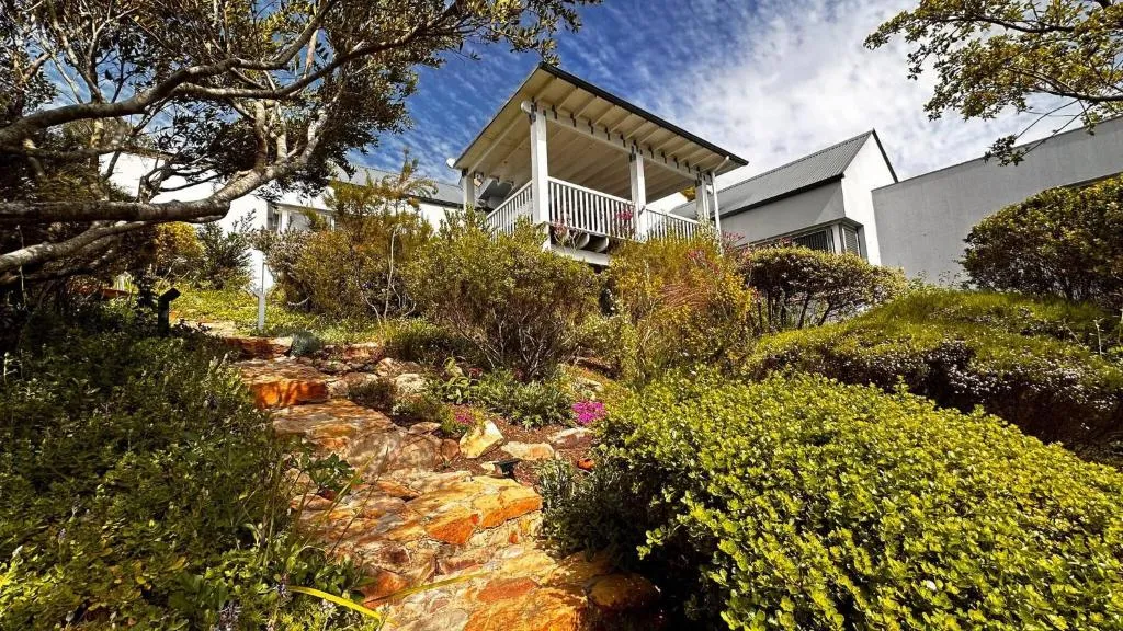Garden path of stone steps climbing past shrubs to the covered upper-deck entrance