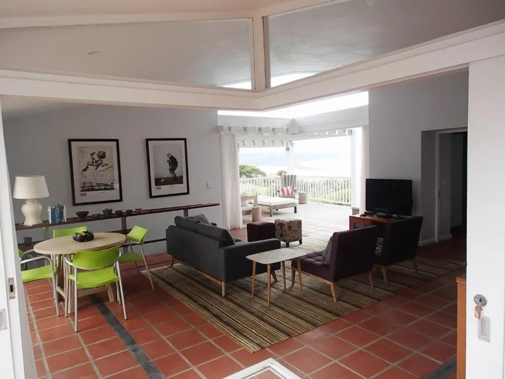 Open-plan lounge and dining area opening through French doors onto a covered deck over the sea