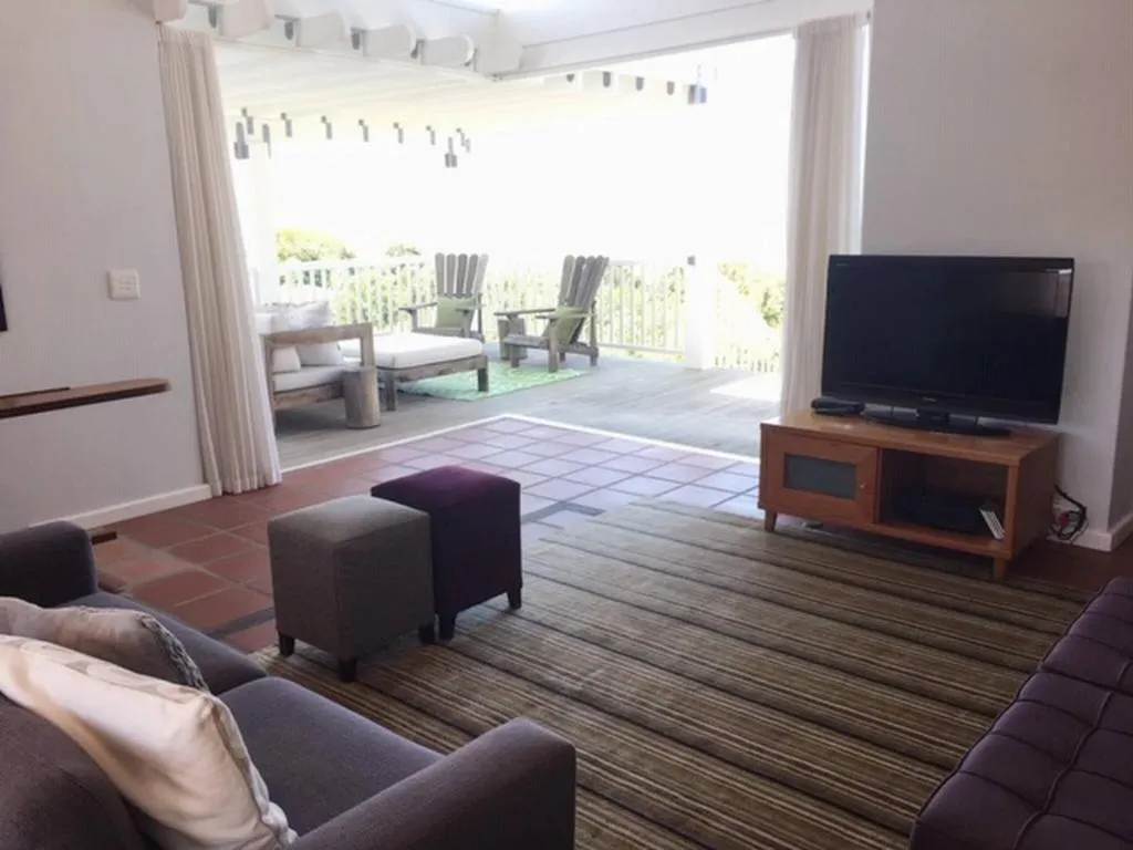 Second lounge with sliding doors onto a pergola-covered deck with outdoor lounge chairs