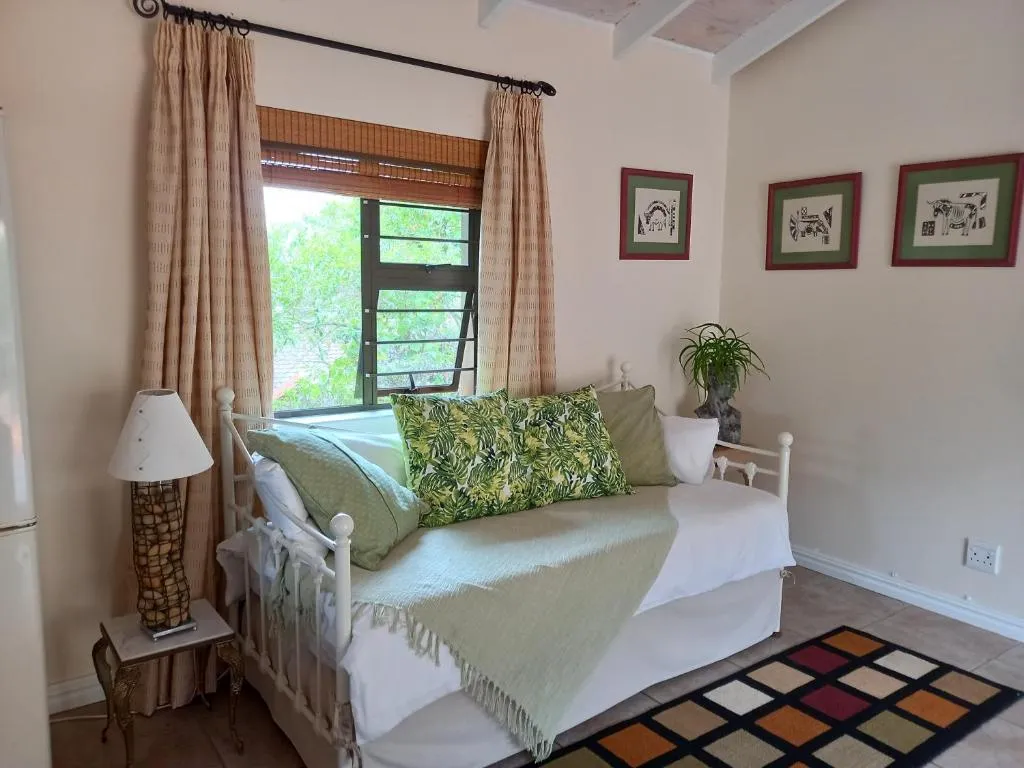Daybed-style bedroom with white iron frame, floral cushions and garden-facing window