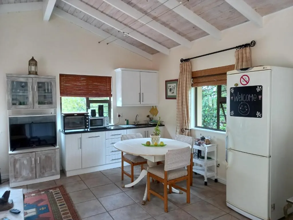Kitchen and round dining table beneath a raftered, whitewashed ceiling