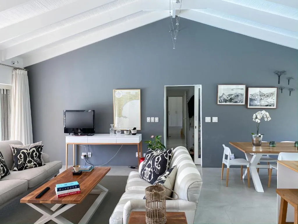 Living room with a grey-blue accent wall, striped sectional sofa and a dining table beyond
