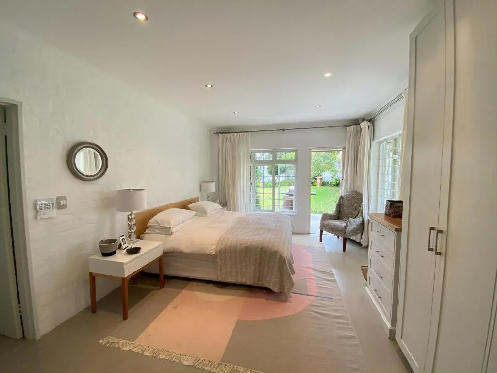 Main bedroom with a king bed, round mirror and glass doors opening directly onto the garden