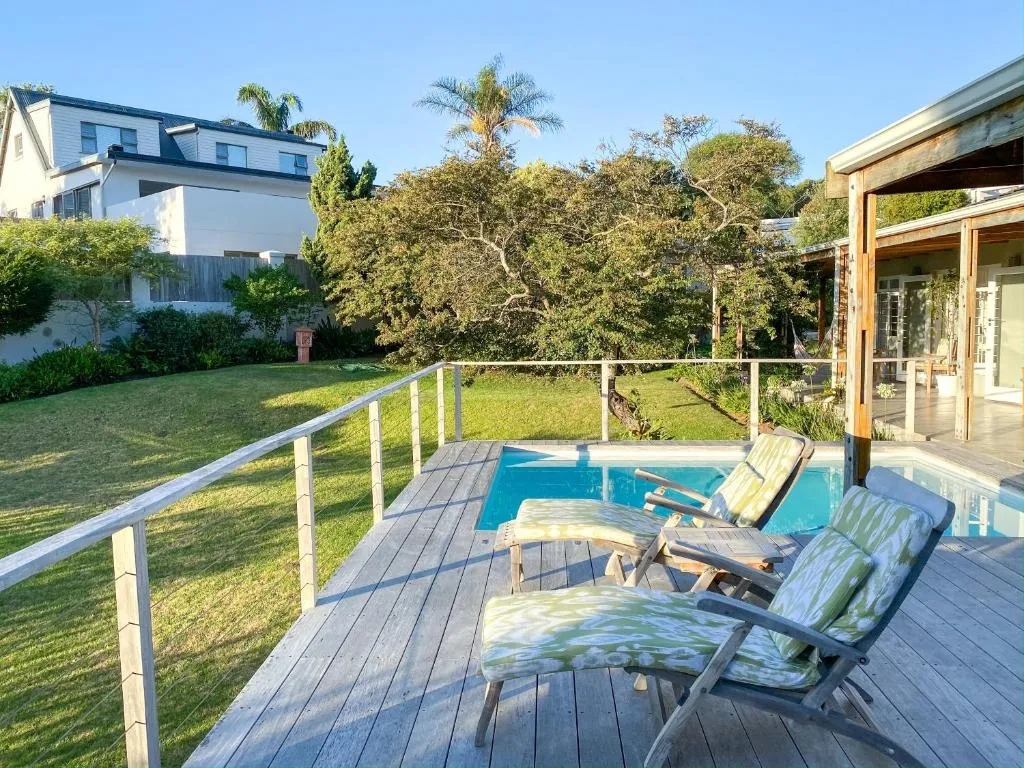 Poolside deck with two patterned loungers overlooking a lawned garden and neighbouring rooftops