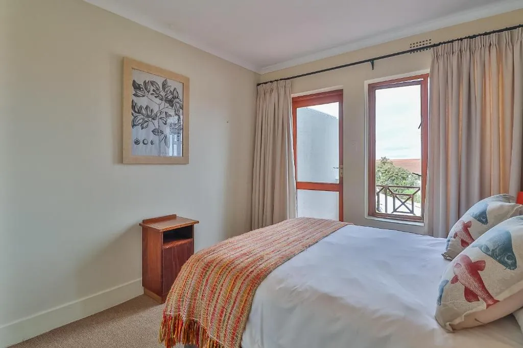 Bedroom with a double bed, fish-print cushions and a balcony over the rooftops
