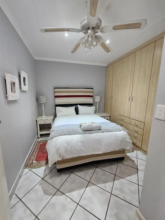Bedroom with built-in wooden wardrobes, a striped headboard and tiled flooring