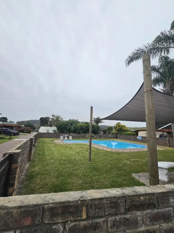 Shared complex pool set in an open lawn area under a large shade sail