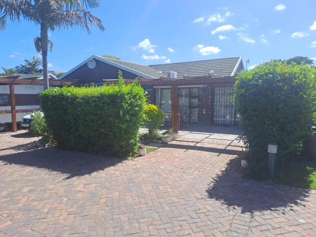 Single-storey unit exterior with a brick driveway, hedges and covered parking