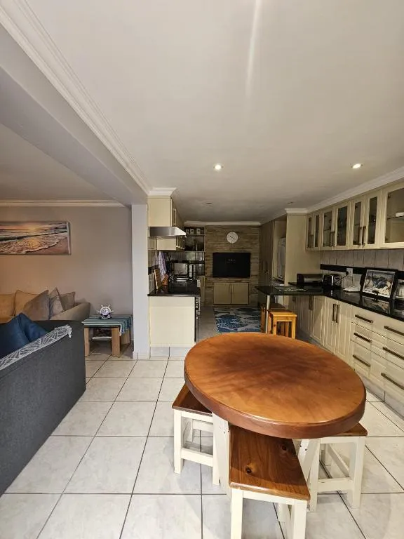Open-plan kitchen and living area with beige cabinetry and a round wooden table