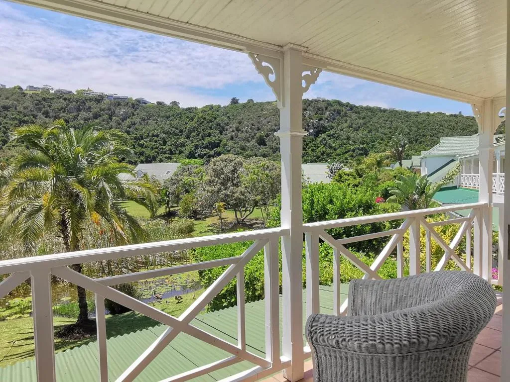 Private balcony with a wicker chair overlooking the lagoon, waterbirds and a forested hillside