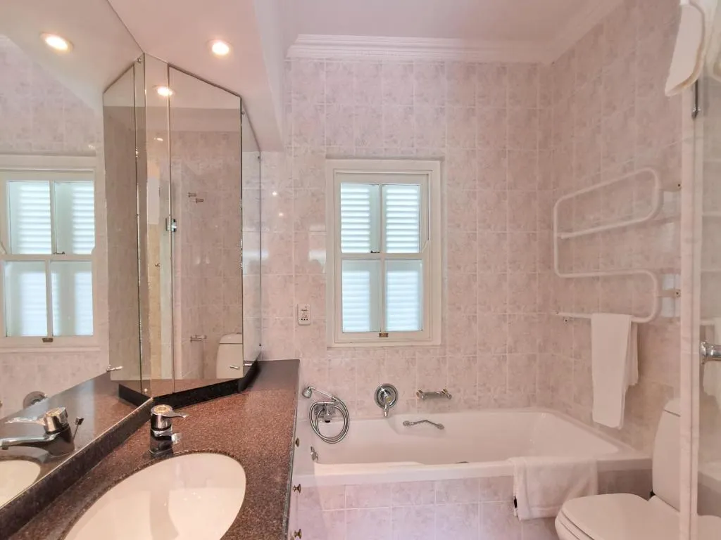 Bathroom with a dark stone vanity counter, bathtub and frosted-glass window