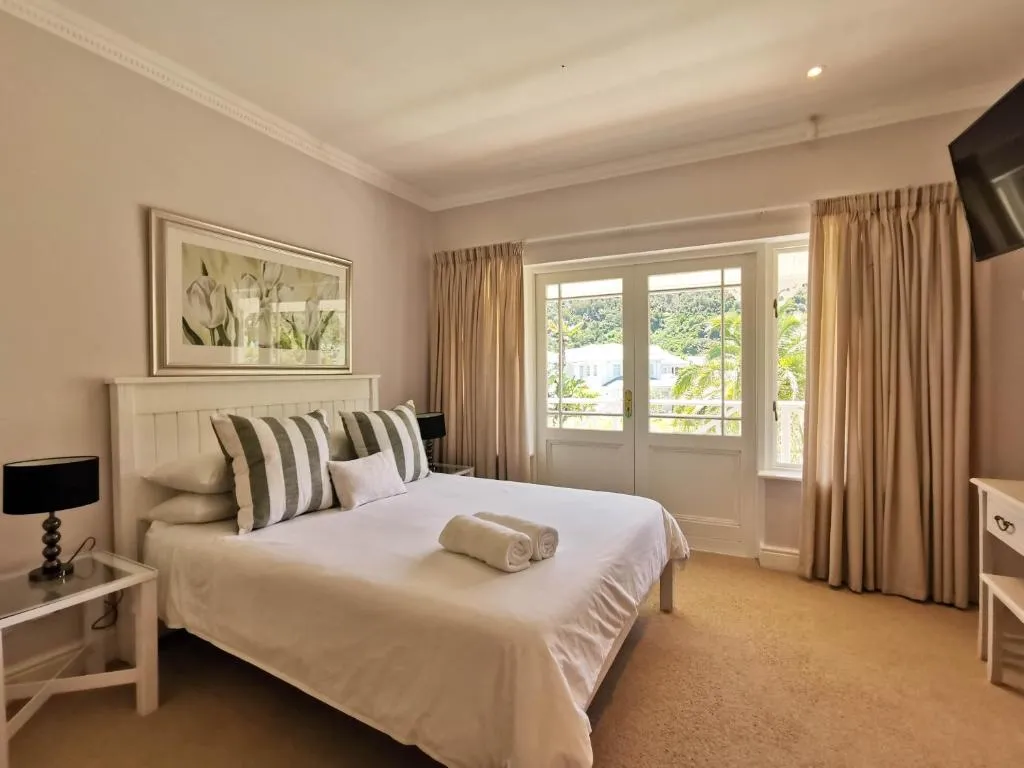 Bedroom with striped cushions and French doors opening onto a private balcony