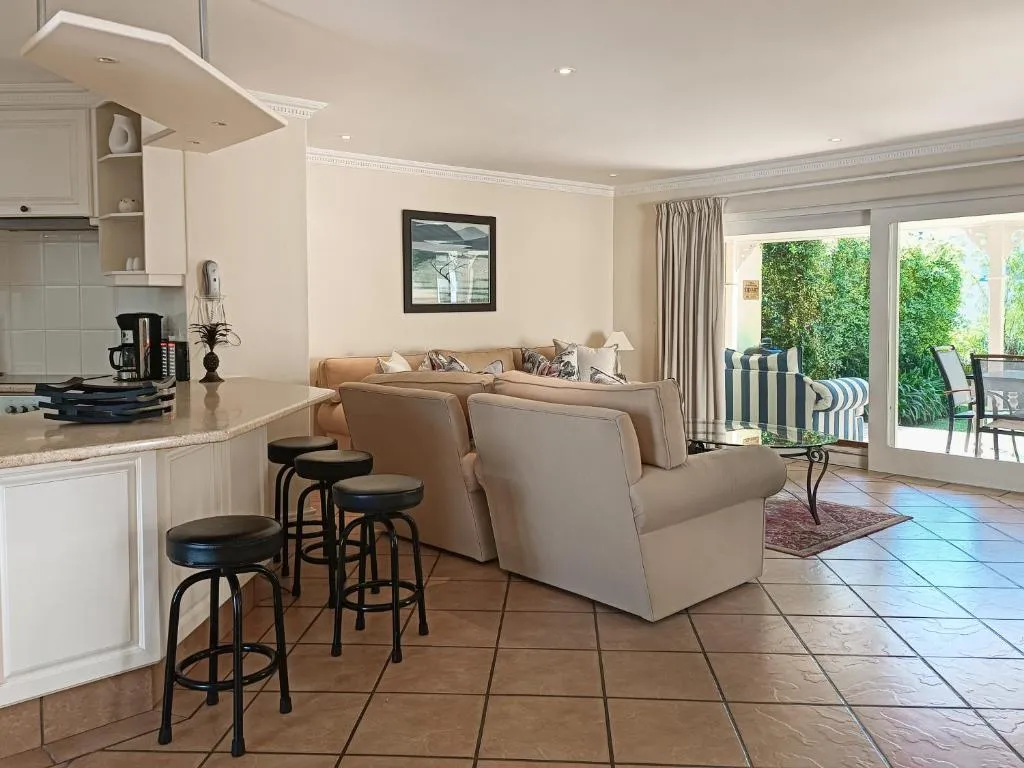 Open-plan kitchen with breakfast bar stools opening onto the living area and garden patio