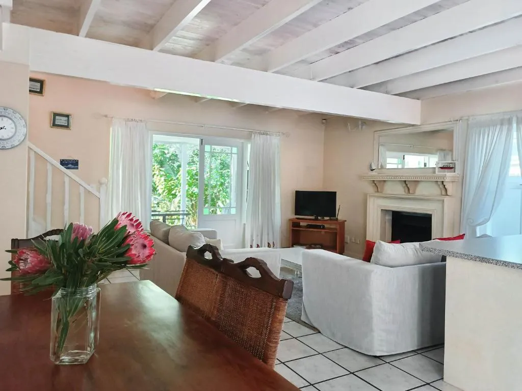 Open-plan living and dining area with a fireplace, staircase and fresh protea flowers on the table