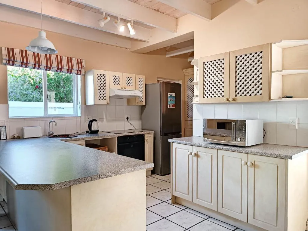 Kitchen with cream cabinetry, a gas hob, built-in oven and a garden-facing window