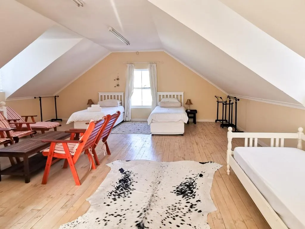 Loft-style bedroom under the eaves with two single beds, a daybed and a cowhide rug