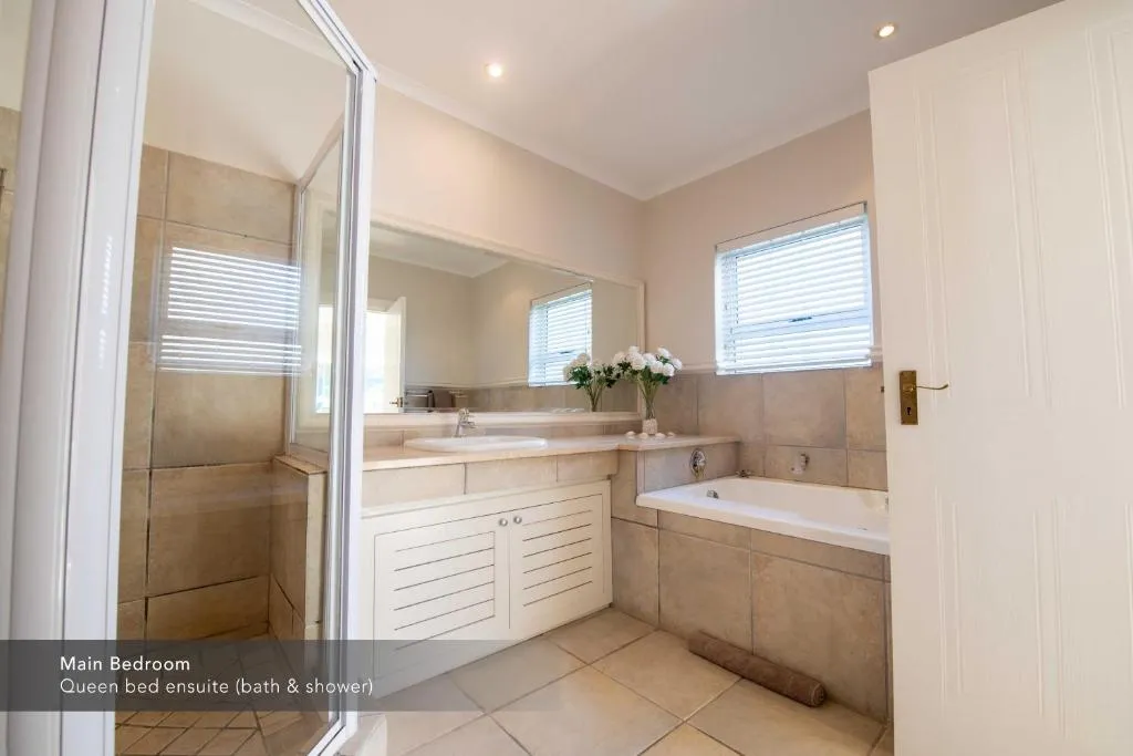 En-suite bathroom with a corner bath, separate glass shower and a large vanity mirror
